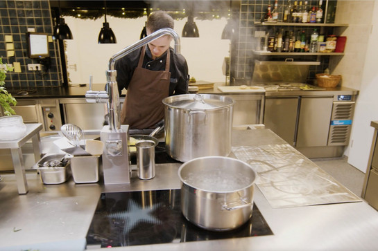 Gastronomieküche, in der ein Koch am Herd steht 