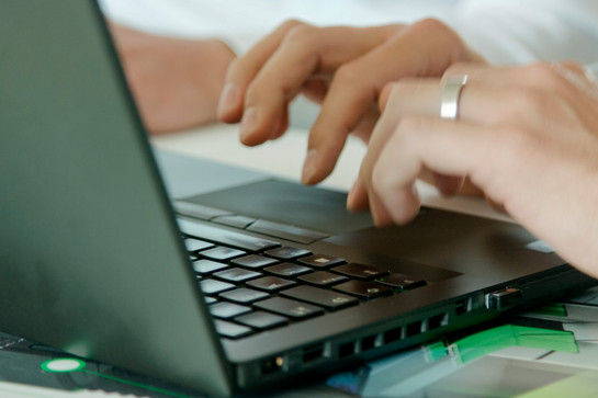 Ein Mann tippt auf einen schwarzen Laptop