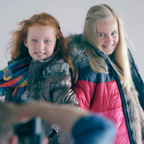 Ein Fotograf fotografiert zwei junge Mädchen, die Winterkleidung tragen.