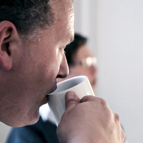 Guter Service ist kein Bank Geheimnis Ein Mann trinkt aus einer weißen Tasse