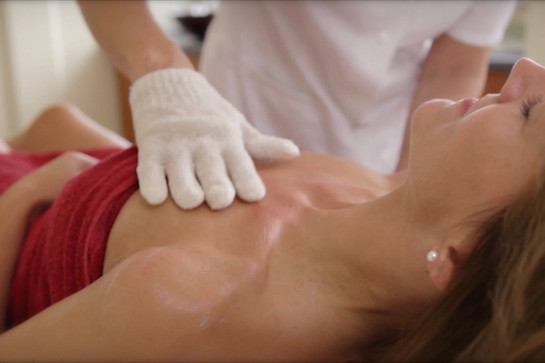 Eine Masseurin massiert das Dekoltee einer Frau