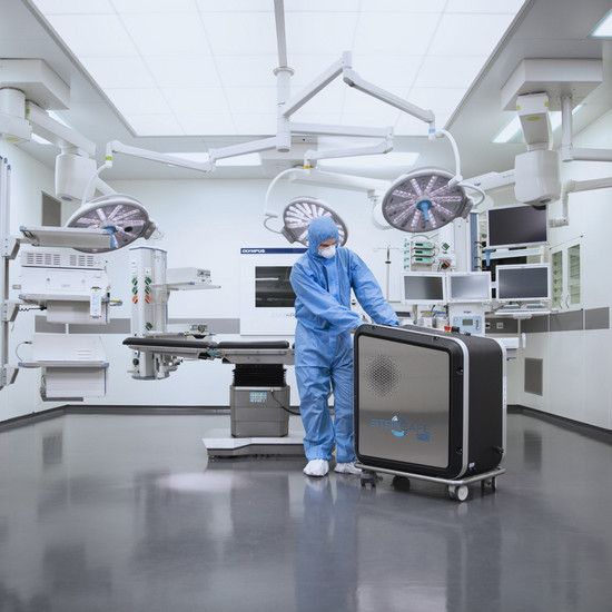 Person im blauen Ganzkörperanzug steht im OP-Saal