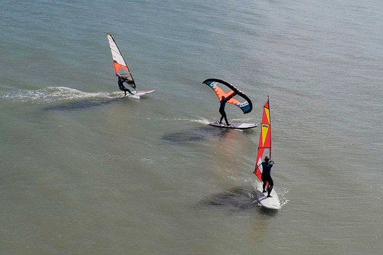 Drei Windsurfer stehen auf dem Wasser