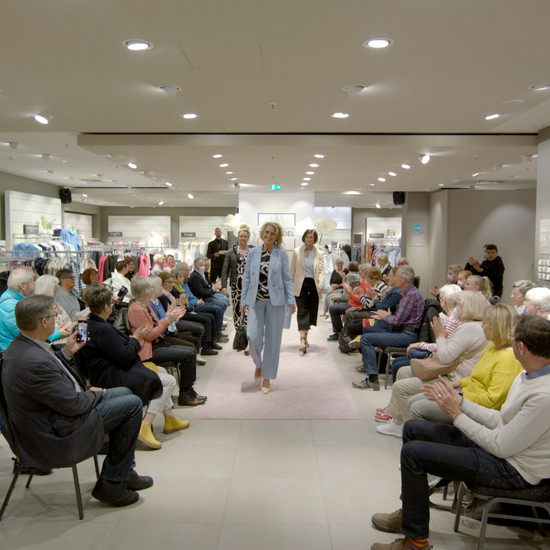 Blondes Topmodel läuft im blauen Hosenanzug über den Laufsteg