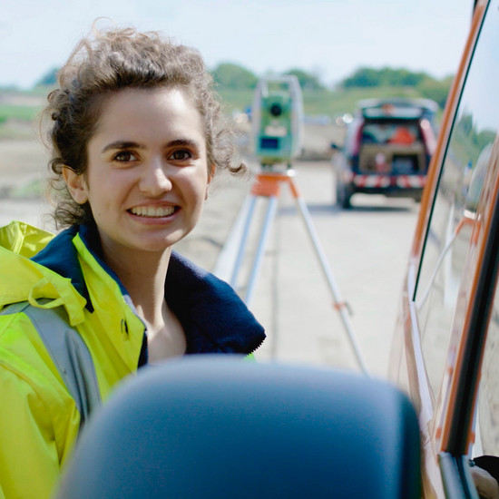 Eine Frau mit lockigem Haar trägt eine Gelbe Warnweste