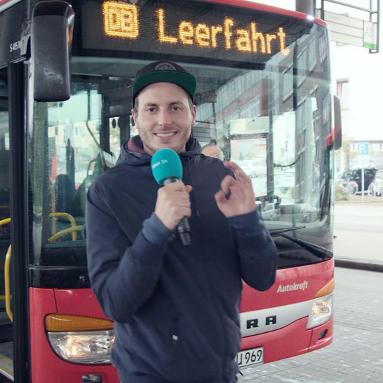 Busfahrer Helmut Ein Mann steht mit seinem Mikro vor einem Bus