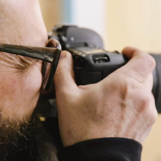 Ein Mann guckt durch die Linse einer Kamera