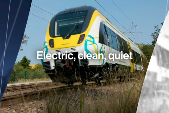 Ein elektrisch betriebener Zug fährt durch die Landschaft.