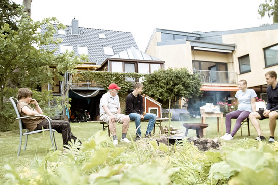 Anna Bandholt sitzt im Garten mit Freunden