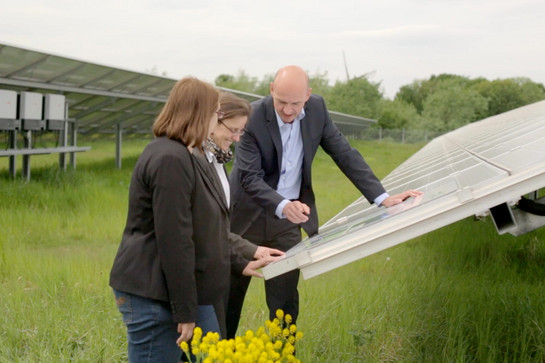 Drei Personen begutachten eine Solarplatte