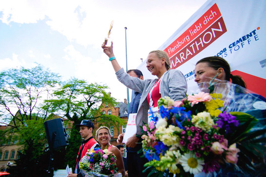 Eine Marathonläuferin hält ihren Preis in die Luft