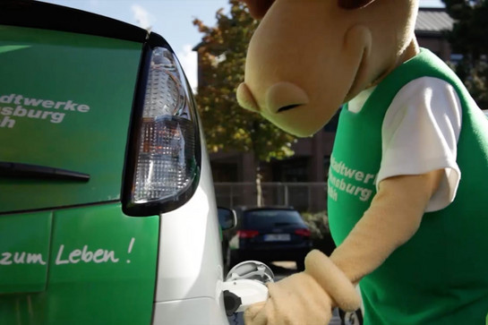 Ein Maskotchen der Stadtwerke Flensburg tankt ein Auto