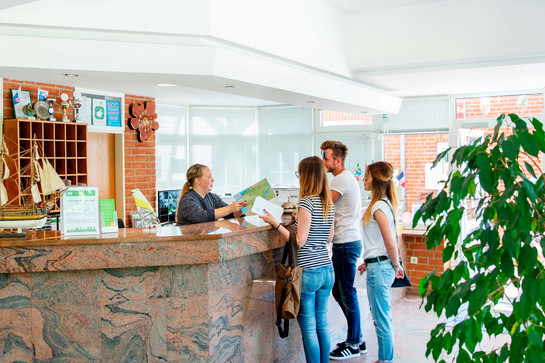 Drei Personen stehen zum Check Inn an der Rezeption