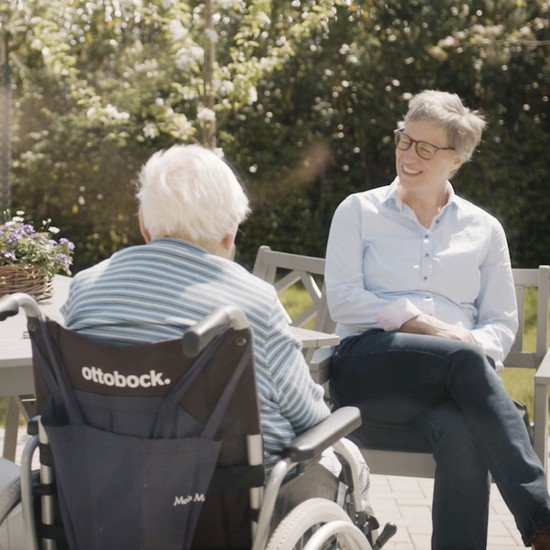 Zwei Frauen sitzen im Park und befinden sich in einem Gespräch.