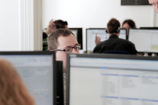 Blick über einen Bildschirm auf einen TDC Mitarbeiter