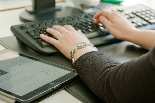 Eine Frau tippt auf einer schwarzen Tastatur