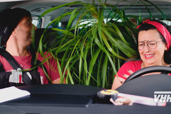 Zwei Personen sitzen im Auto und haben eine Pflanze auf dem Rücksitz