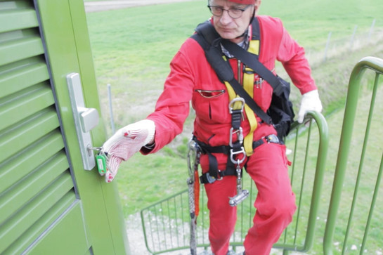 Ein Mann in roter Arbeitskleidung schließt eine Tür auf