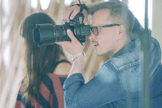 Junger Mann mit Jeansjacke fotografiert mit einer Spiegelreflexkamera