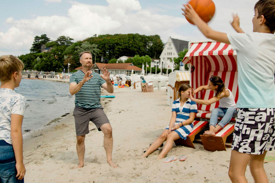 Eine Familie spielt Ball am Strand
