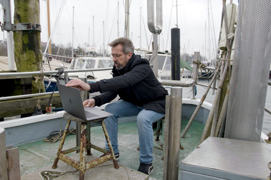 Mann mit Laptop auf Fischkutter