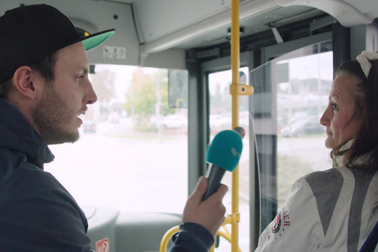 bb_helmut_teaser_05.jpg Ein Mann interviewt eine Frau die vorne im Bus sitzt