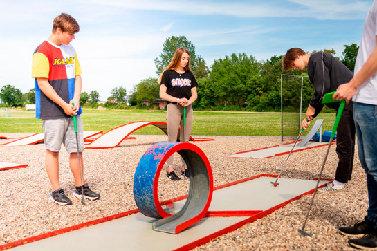 Eine Gruppe Jugendlicher spielen Minigolf