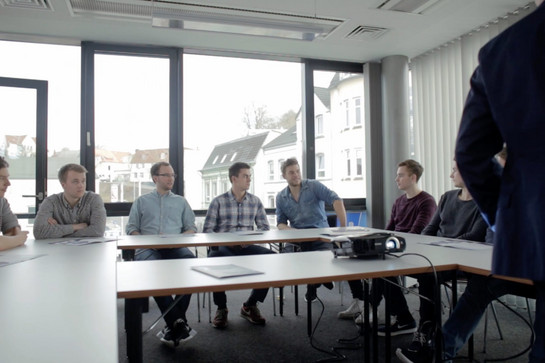 Eine Gruppe von jungen Männer sitzen in einem Hufeisen