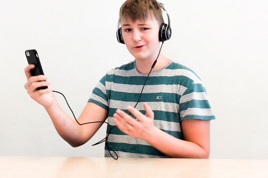 Ein Junge im gestreiften Oberteil hört Musik über Kopfhörer