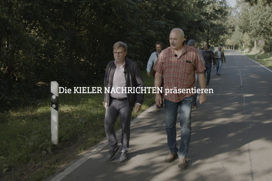 Personen gehen auf einer Landstraße