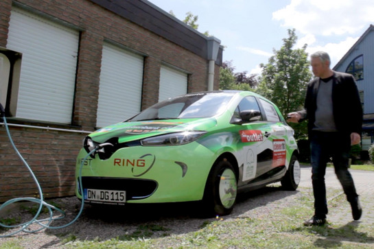 Grünes E Auto lädt an einer Ladestation