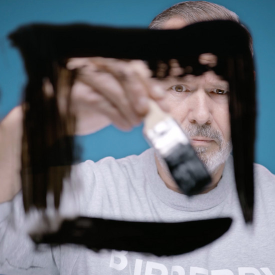 Ein Mann malt mit schwarzer Farbe ein viereck