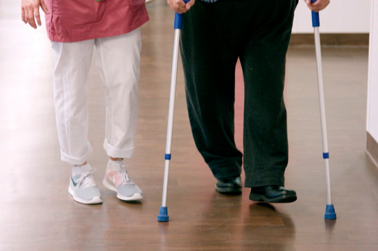 Eine Krankenschwester hilft einem alten Patienten beim gehen