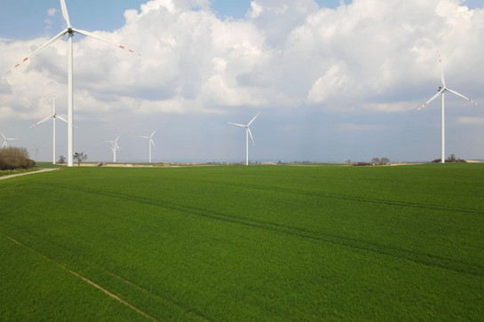 Blick auf eine grüne Wiese mit drei Windrädern