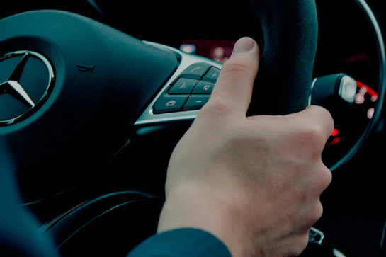 Eine Person hält das Lenkrads eines Mercedes Benz