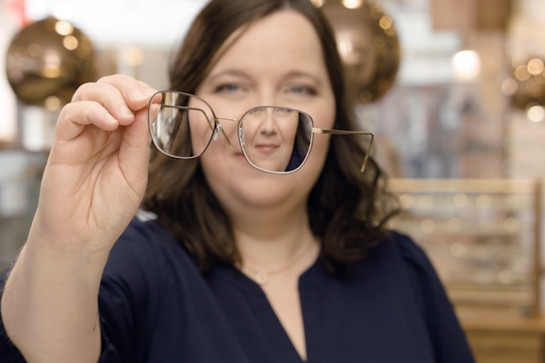 Optikerin hält eine Brille in die Kamera