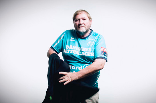 Ein älterer Mann trögt ein blaues SG Shirt