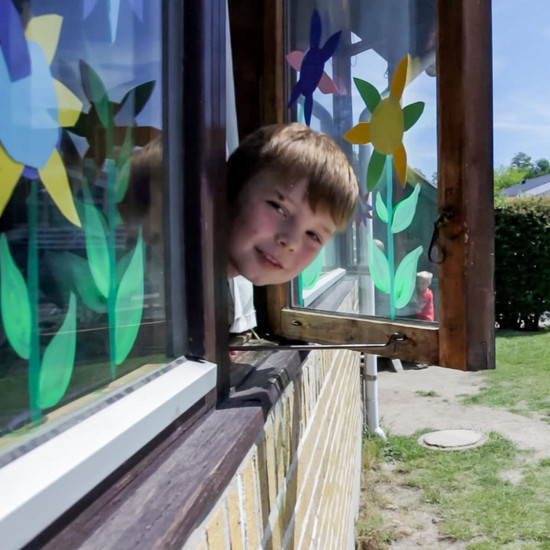 Kleiner Junge blickt aus Fenster direkt in die Kamera