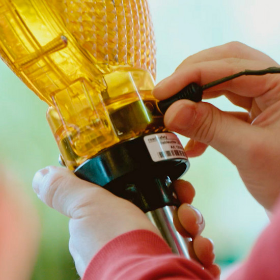 Eine Person schraubt an einer Baustellenbeleuchtung