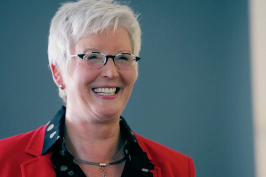 Eine grauhaarige Frau im roten Blazer