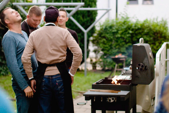 Vier Personen stehen vor einem Grill