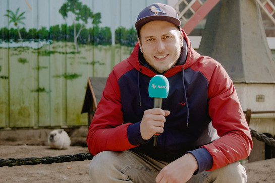 Lars sitzt vor einem Kaninchengehege