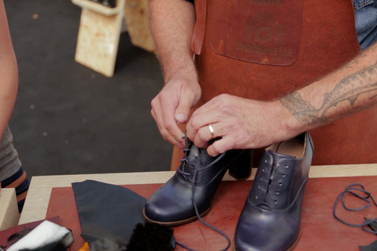 Ein Schuhmacher schnürt Schuhe