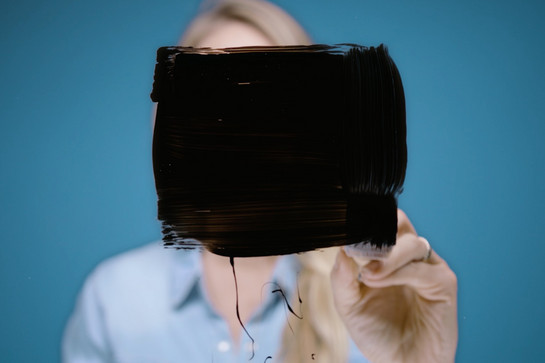 Eine Frau malt ein schwarzes Viereck auf eine Glasscheibe