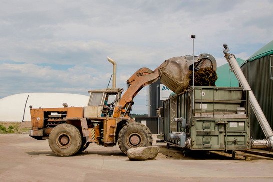 Ein Bagger lädt etwas in einem Container ab
