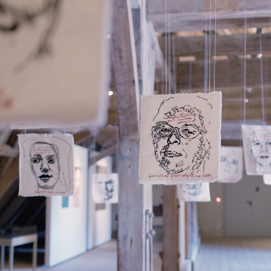Von der Decke hängende Stoffzuschnitte mit Skizzen von verschiedenen Gesichtern