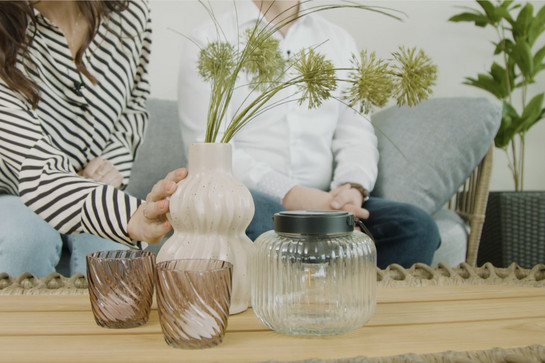 Vase mit Blume, 2 Teelichtgläser und eine Glaslaterne auf einem Holztisch