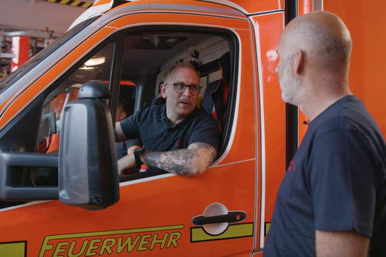 Ein Feuerwehrmann lehnt sich aus dem Fenster des Feuerwehrautos