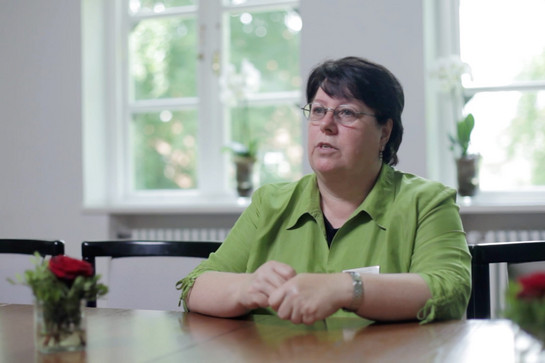 Ein Standbild einer Frau im grünem Hemd