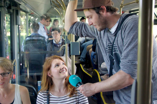 Ein Nah.Ssh Moderator interviewt eine Frau im Bus